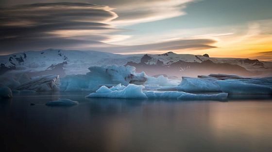 Icebergs in thr water mountains in the background